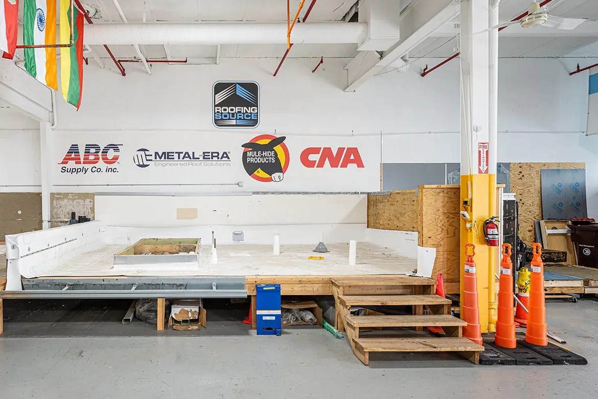Manufacturer and association marks mounted on the wall above a training deck at headquarters, flags hanging overhead.