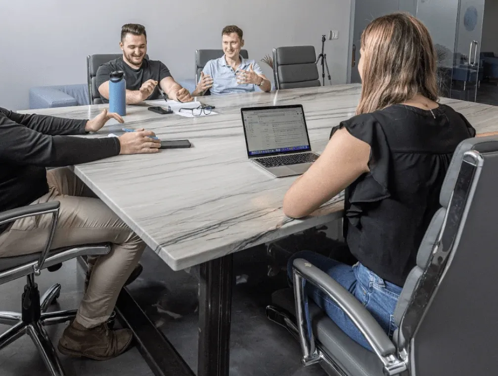 Four teammates in conversation around the conference table at HQ.