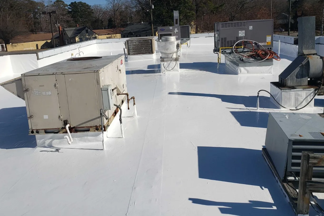 A commercial roof crowded with rooftop units under a new white reflective coating