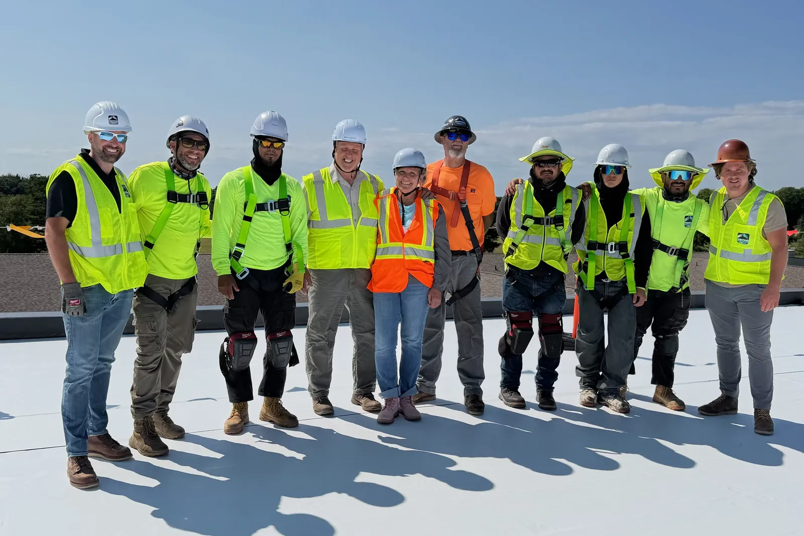 A RoofingSource production crew in hi-vis and hard hats lined up on a finished roof