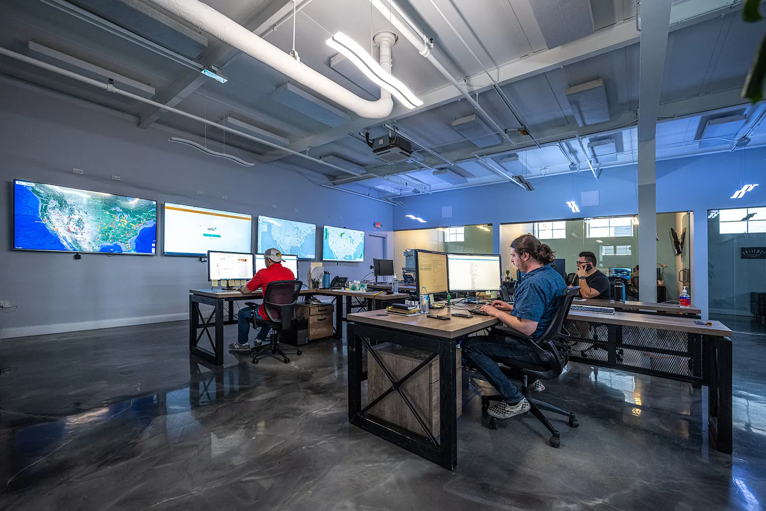 Teammates at desks under a wall of live operations screens at headquarters.