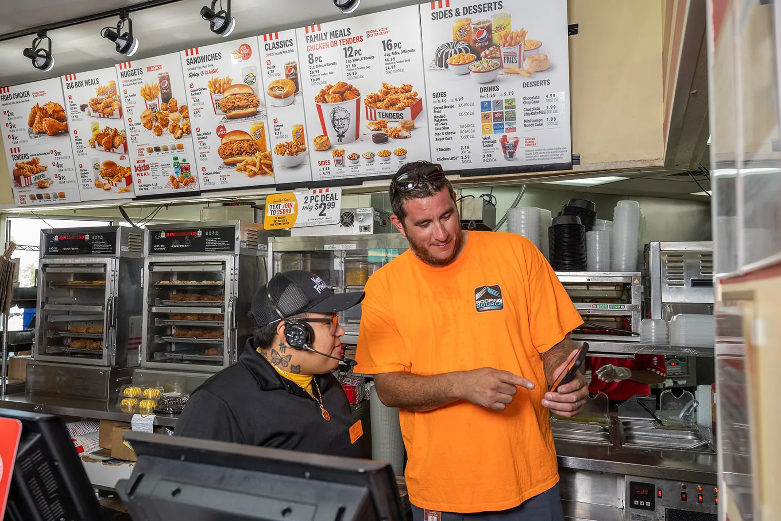 A RoofingSource teammate showing a restaurant manager a report on a tablet