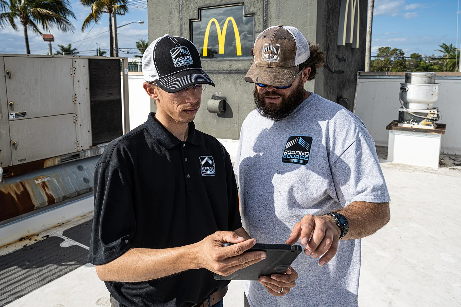Two RoofingSource teammates reviewing a tablet together on a client's roof.