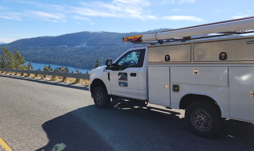 A RoofingSource service truck on a mountain road above a lake
