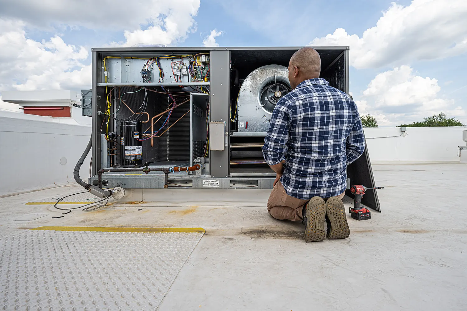 A teammate kneeling inside an opened rooftop unit