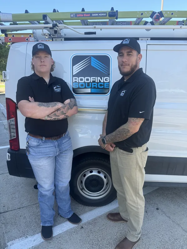 Two teammates standing beside a RoofingSource van.
