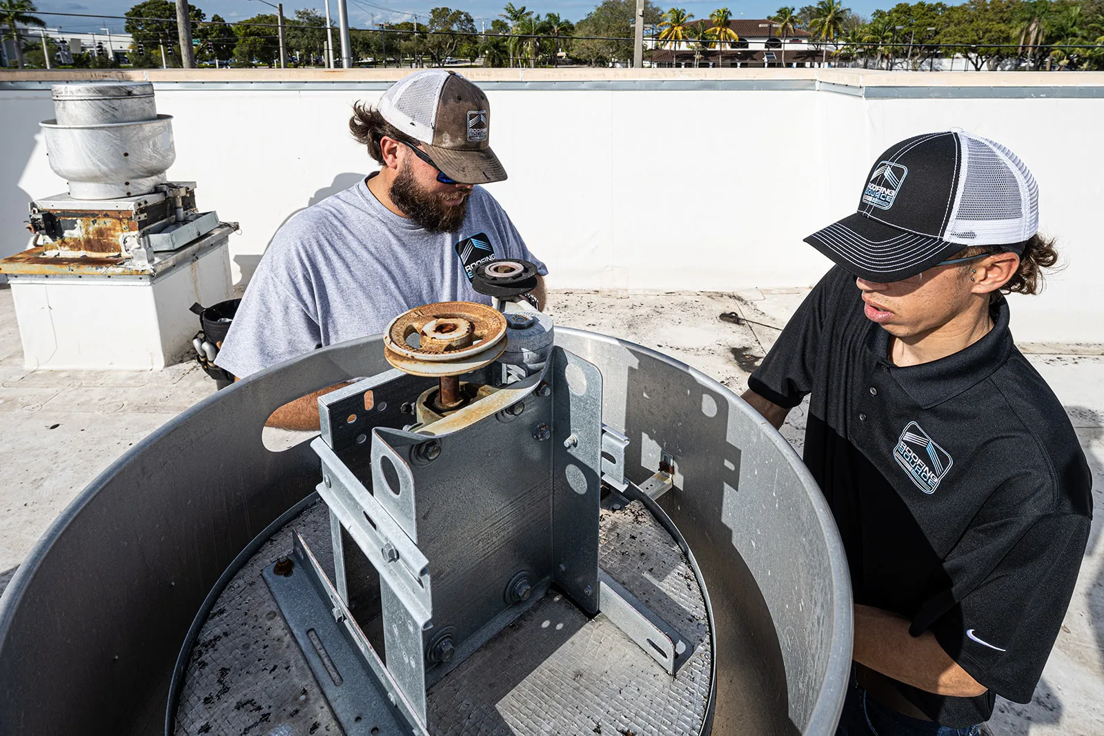 Two RoofingSource teammates at an opened rooftop exhaust unit