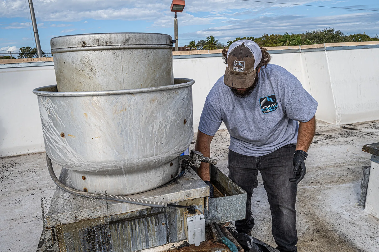 A RoofingSource technician working inside an open rooftop grease ventilator