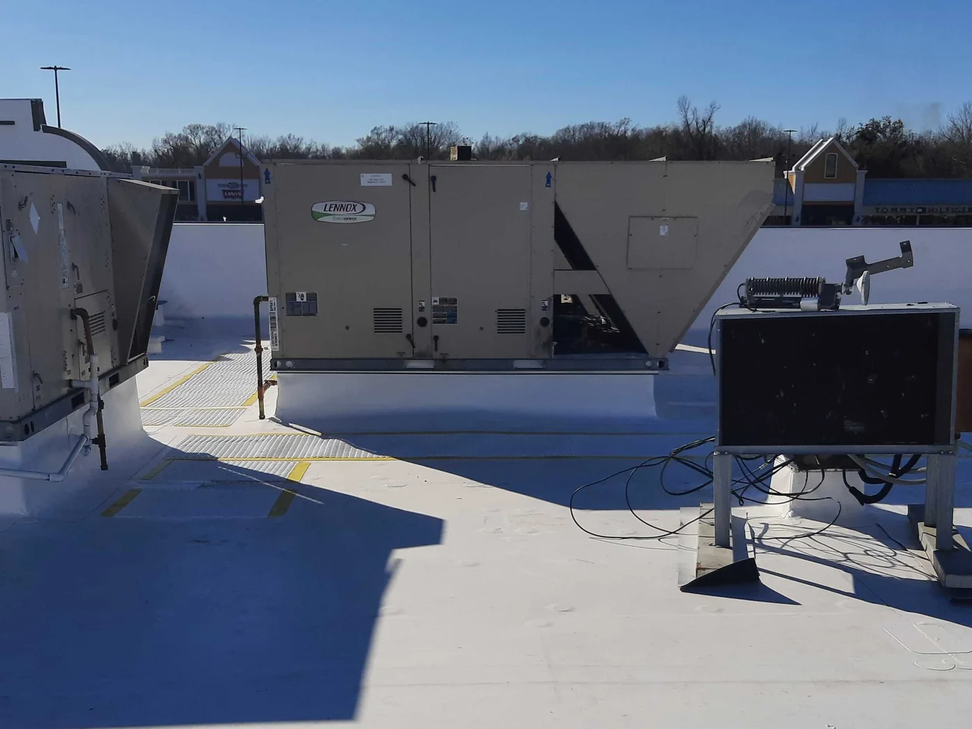 A white commercial roof with its rooftop units, the surface running unbroken up to the unit curbs