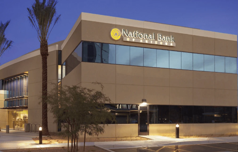 A National Bank of Arizona branch at dusk, its lit sign along the upper storey.