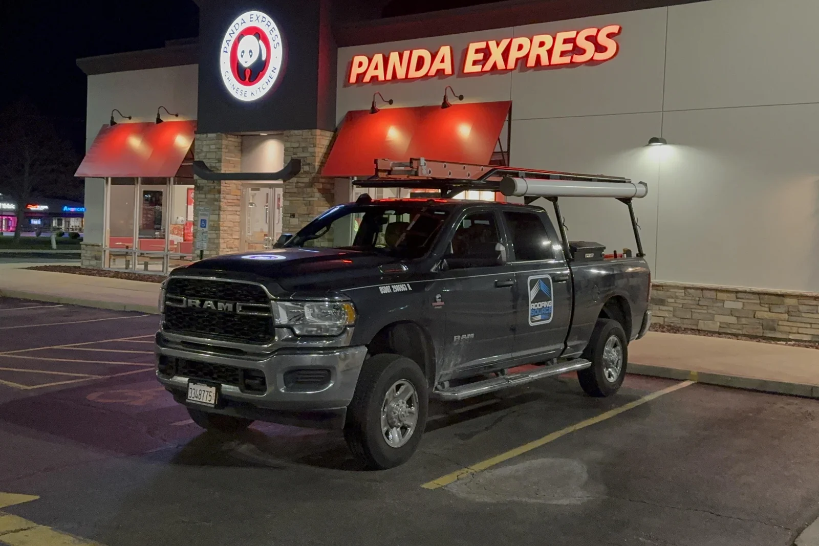 A RoofingSource service truck parked outside a Panda Express at night, the restaurant sign lit above it
