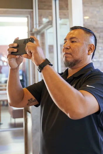 A Field Advisor holding up his phone to photograph the ceiling inside a restaurant dining room