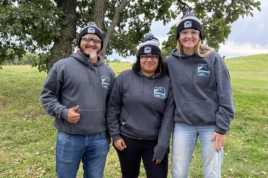 Three teammates in RoofingSource beanies outdoors on a company day