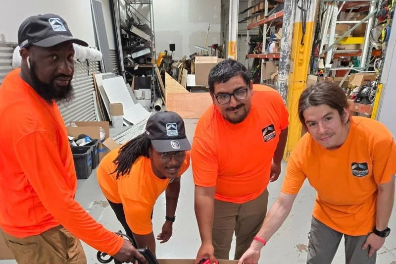 Teammates in RoofingSource shirts packing a box together at a volunteer event