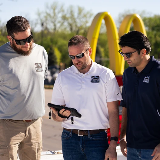 Three RoofingSource teammates walking with tablets outside a McDonald’s restaurant