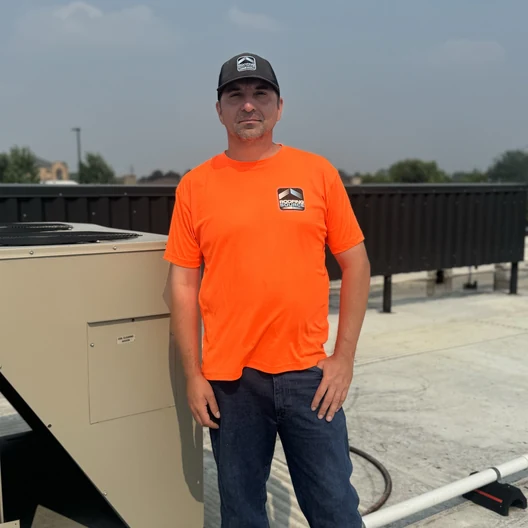 A RoofingSource teammate standing beside a rooftop unit on a job