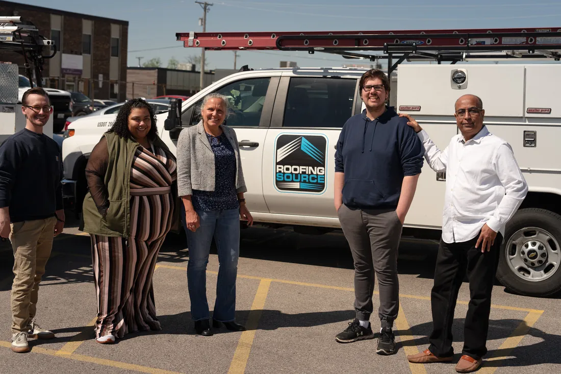 Five RoofingSource teammates beside a service truck outside headquarters