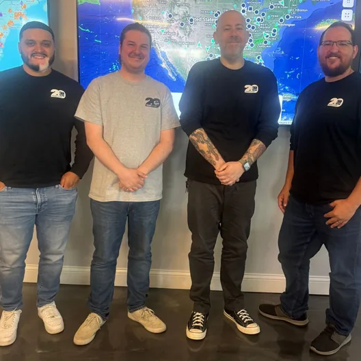 Four RoofingSource teammates in twentieth-anniversary shirts