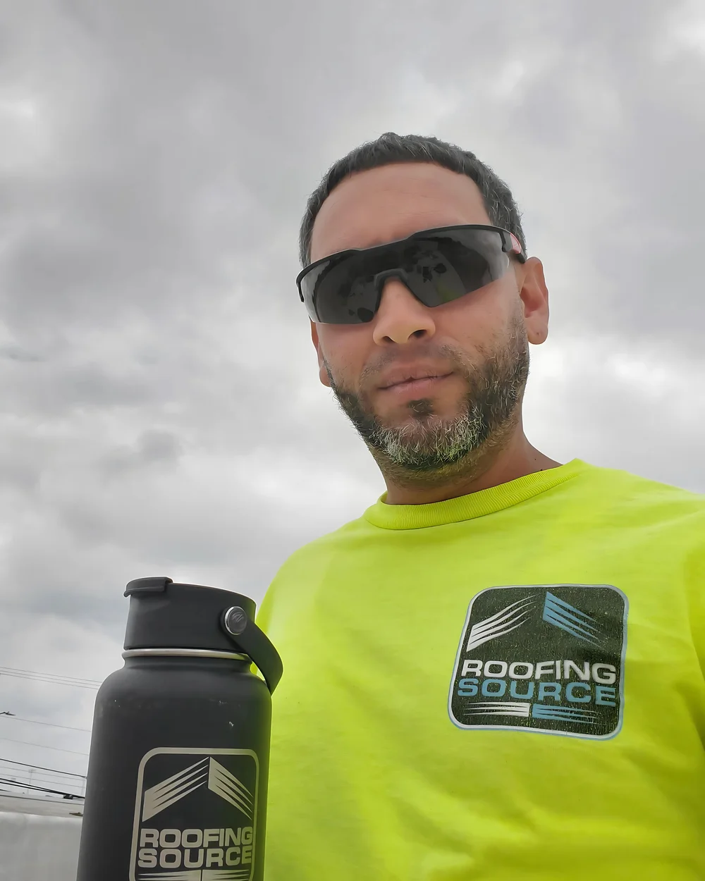A RoofingSource teammate in a hi-vis shirt on a roof