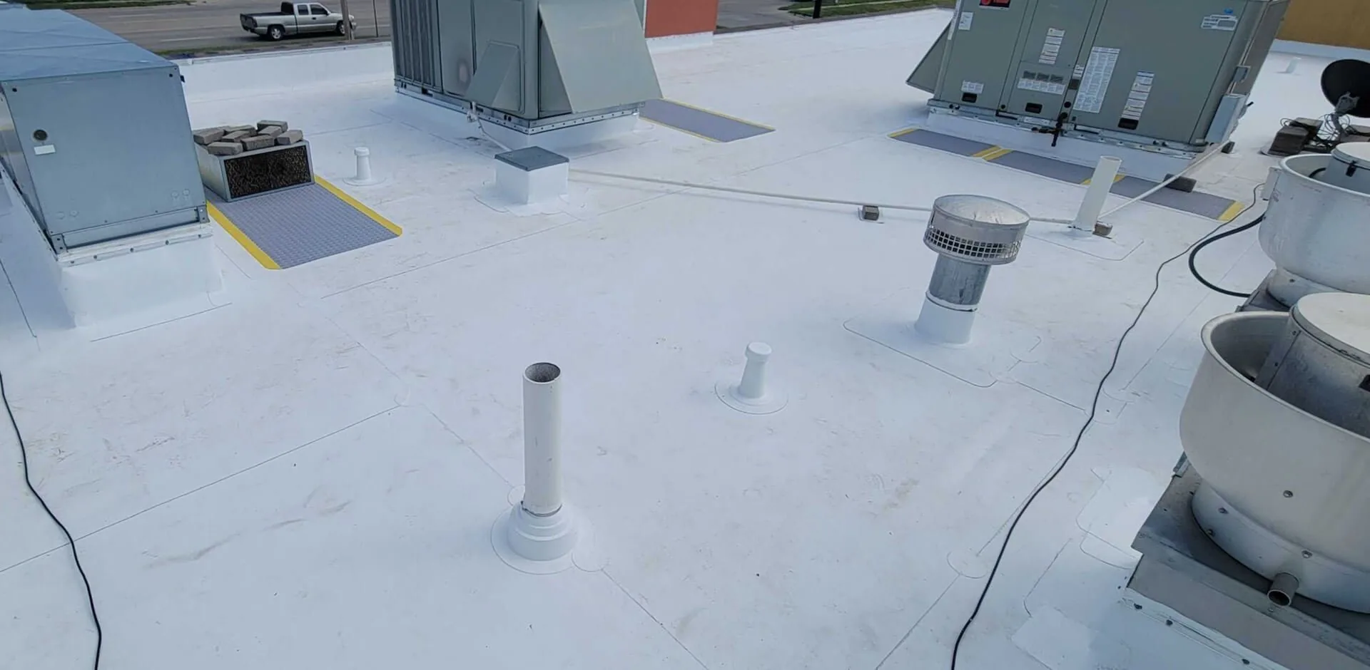 A commercial roof under a new white membrane, its vents and fans flashed in
