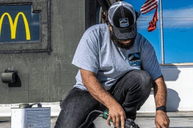 A teammate crouched on a restaurant rooftop, heat-welding a membrane patch
